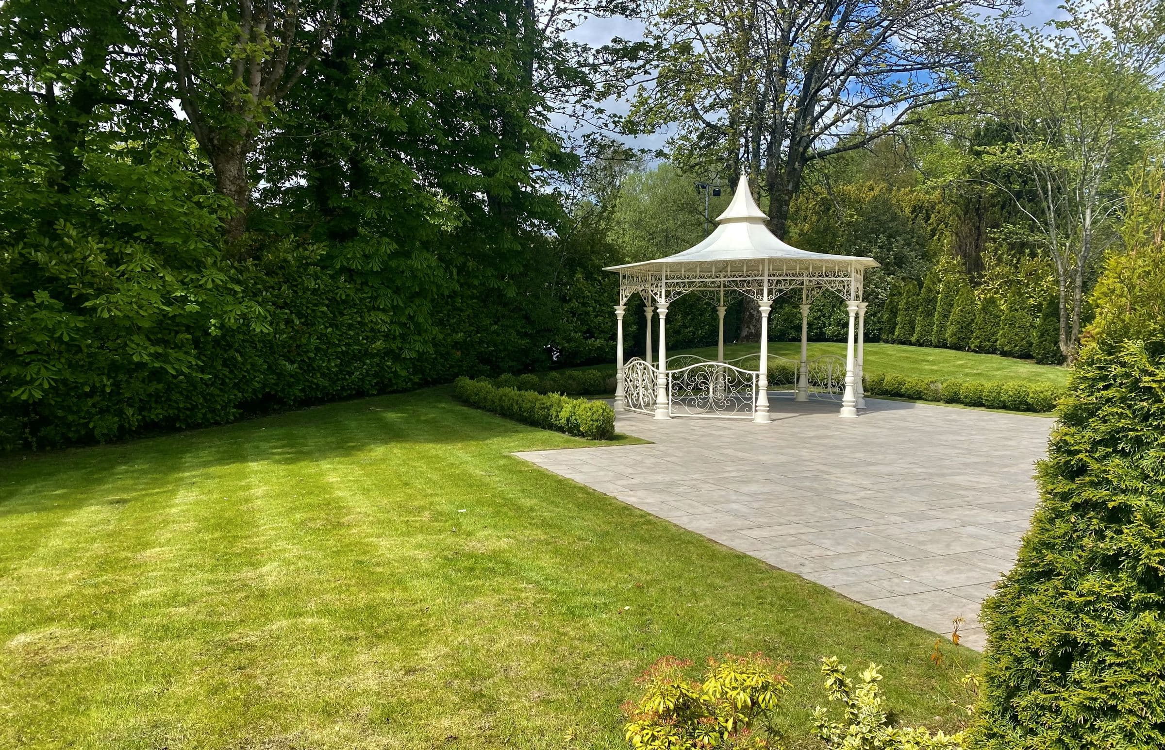 Manicured lawn, clipped hedging and a restored bandstand on grounds maintained by McKay Landscapes Scotland