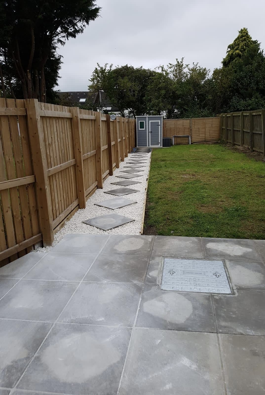Grey porcelain slab path running the length of a fenced rear garden
